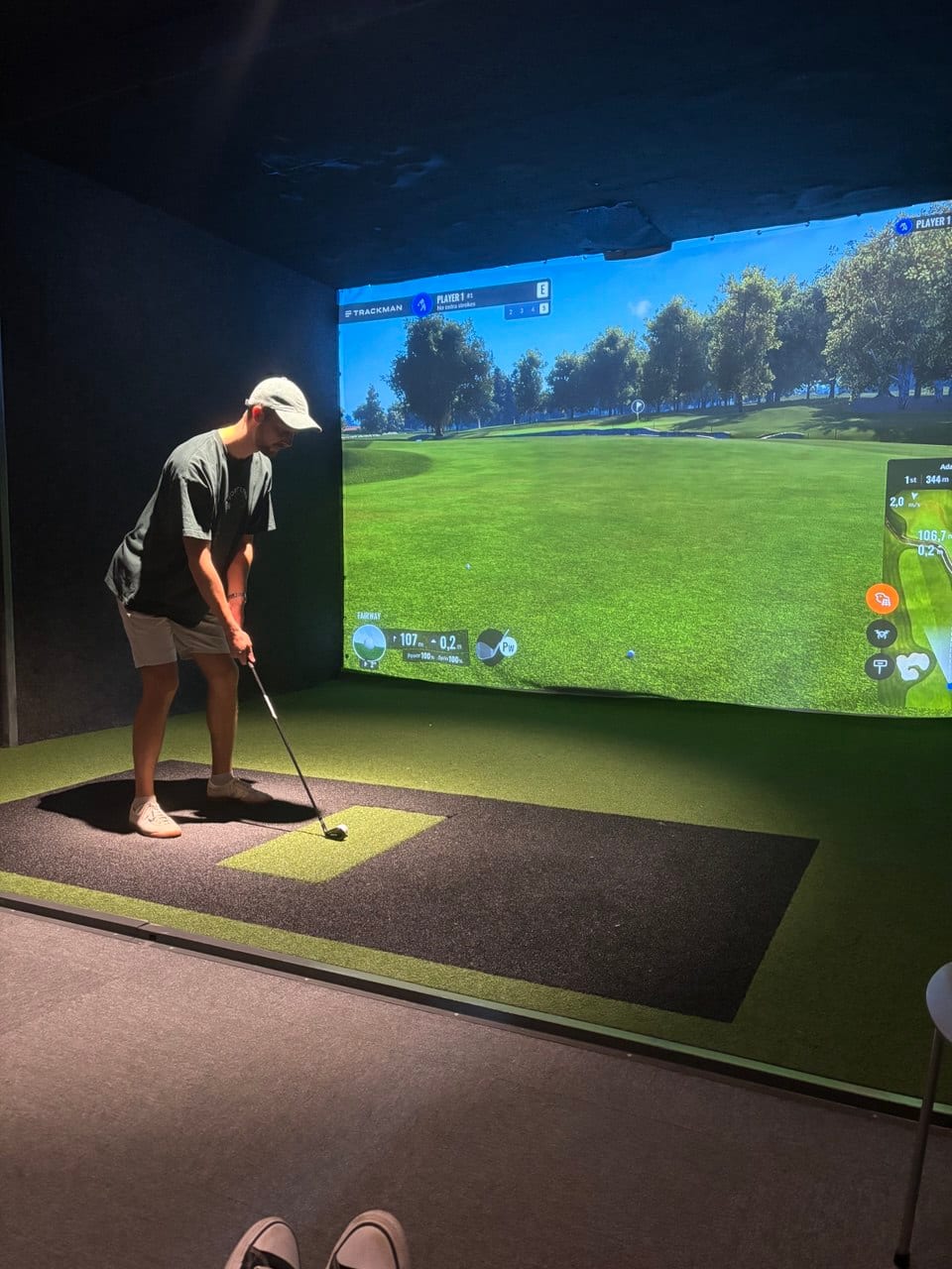 Spelare i keps och shorts som slår i simulatorn